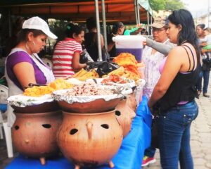 Two women are standing, selling and shopping for food at the fair.